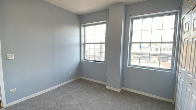 spare room with baseboards and carpet flooring