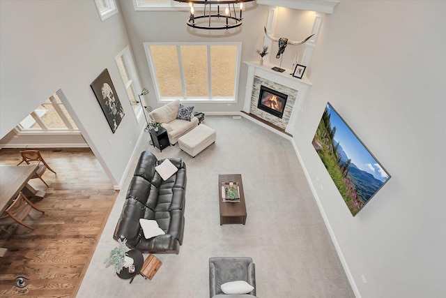 living room with a fireplace, a towering ceiling, baseboards, and wood finished floors