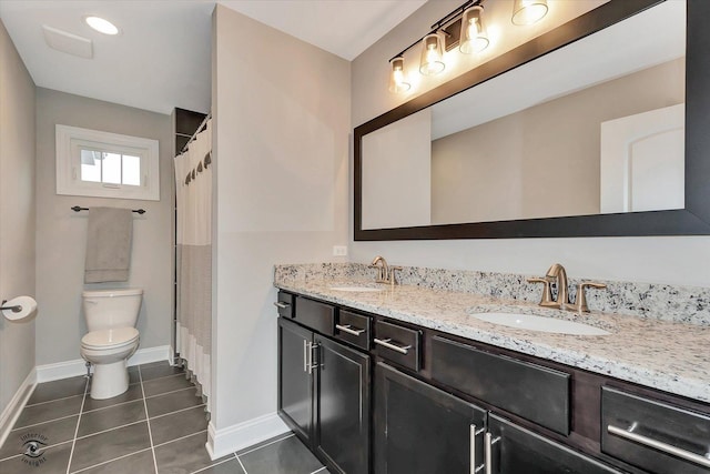 bathroom with double vanity, a sink, toilet, and tile patterned floors