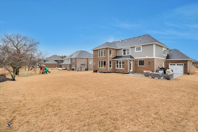 back of property featuring a yard, brick siding, a playground, and a patio