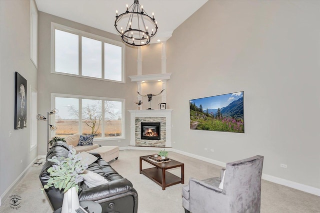 living room featuring a fireplace, a high ceiling, an inviting chandelier, carpet flooring, and baseboards