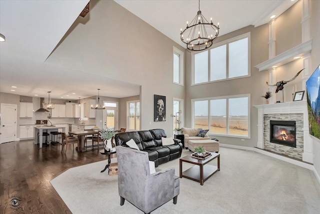 living area with a wealth of natural light, a glass covered fireplace, baseboards, and an inviting chandelier