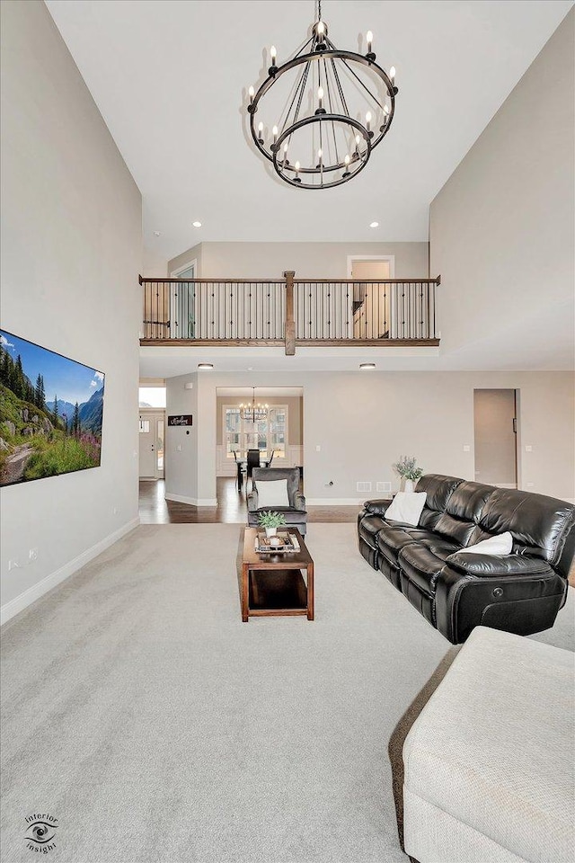 living room featuring baseboards, a towering ceiling, carpet, a notable chandelier, and recessed lighting