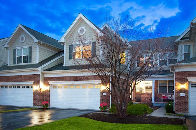 view of front of house featuring brick siding, driveway, an attached garage, and roof with shingles