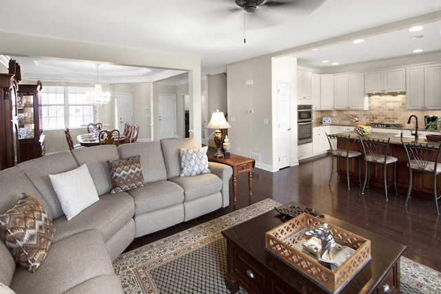 living room featuring dark wood-style floors, recessed lighting, baseboards, and ceiling fan with notable chandelier