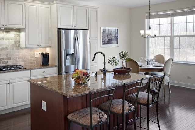 kitchen featuring gas cooktop, dark stone counters, backsplash, and stainless steel fridge with ice dispenser