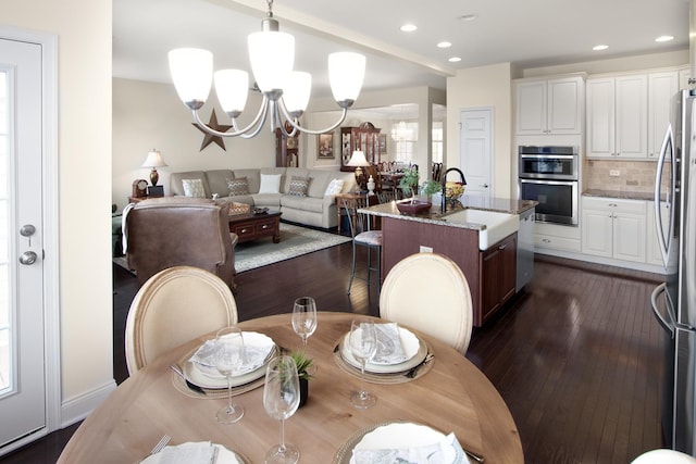 dining area with recessed lighting, dark wood finished floors, and an inviting chandelier