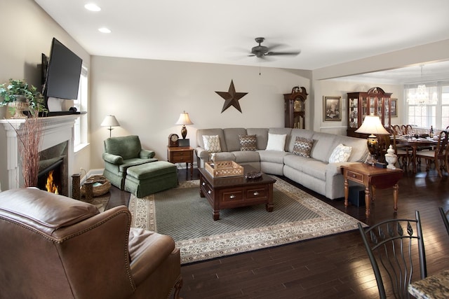 living room with ceiling fan with notable chandelier, a fireplace, wood finished floors, and recessed lighting