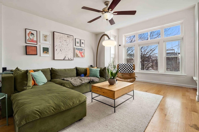 living area featuring baseboards, wood finished floors, and a ceiling fan