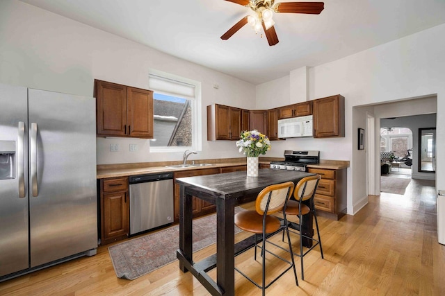 kitchen featuring light countertops, appliances with stainless steel finishes, light wood-style floors, a ceiling fan, and a sink