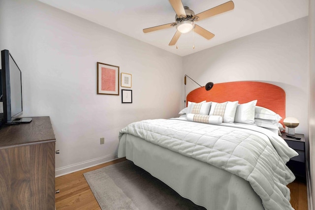 bedroom with ceiling fan, baseboards, and wood finished floors