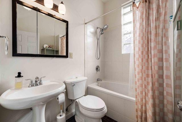 bathroom featuring tiled shower / bath combo, toilet, and a sink