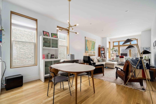 dining space featuring baseboards, light wood-style floors, and a chandelier