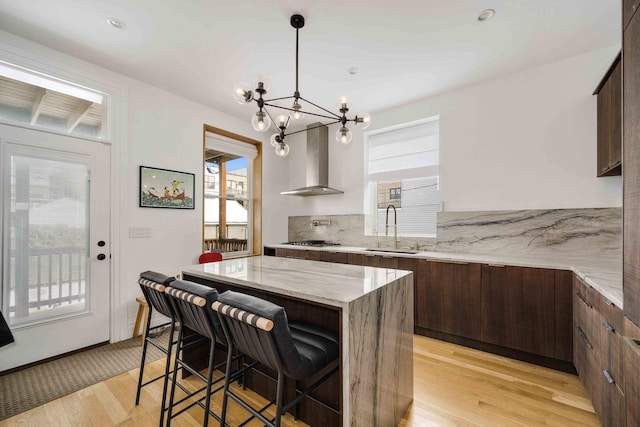 kitchen featuring a sink, plenty of natural light, modern cabinets, and wall chimney range hood