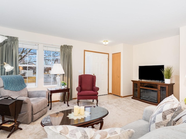 living area featuring baseboards, carpet flooring, and a glass covered fireplace