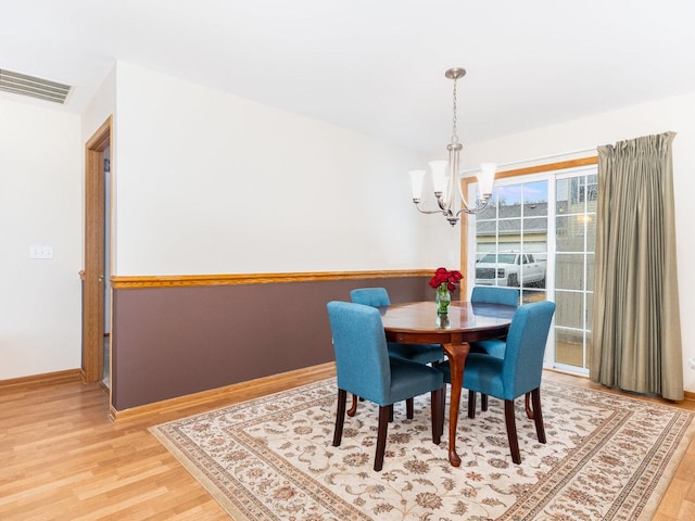 dining area featuring an inviting chandelier, baseboards, visible vents, and light wood-style floors