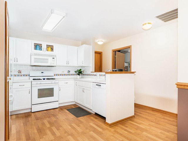 kitchen with white appliances, white cabinetry, visible vents, and a sink