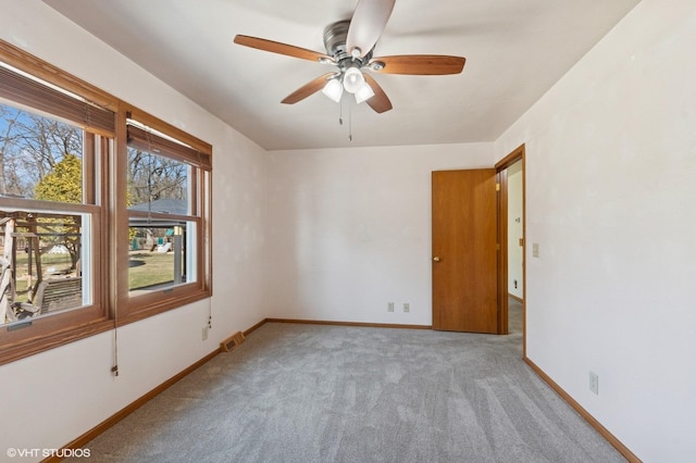 spare room with baseboards, carpet floors, visible vents, and ceiling fan