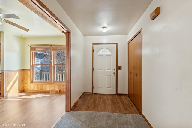 entrance foyer featuring a wainscoted wall, visible vents, wood finished floors, and a ceiling fan