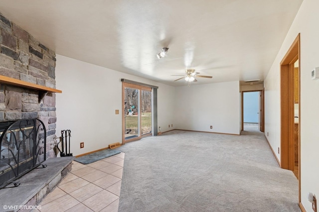 living area with a stone fireplace, light colored carpet, baseboards, and a ceiling fan