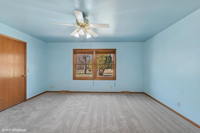 carpeted empty room with visible vents, baseboards, and ceiling fan