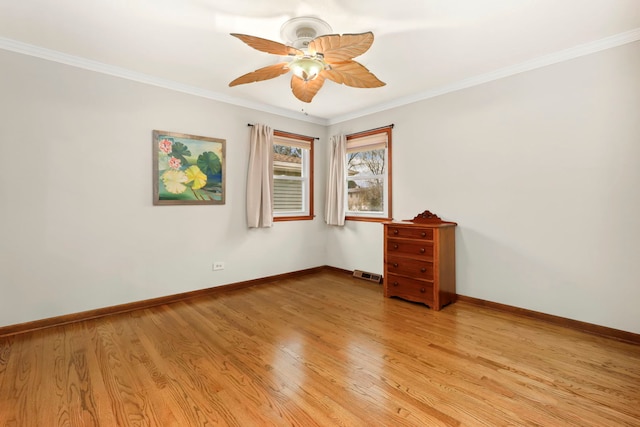 spare room with crown molding, visible vents, light wood-style floors, ceiling fan, and baseboards