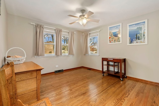 interior space featuring baseboards, a ceiling fan, visible vents, and light wood-style floors