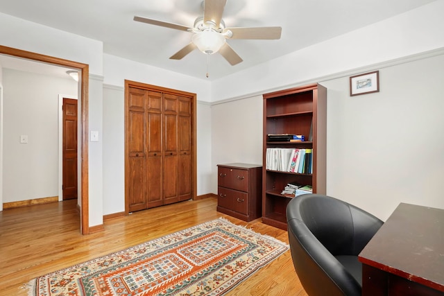 office featuring a ceiling fan, light wood-type flooring, and baseboards