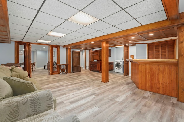 unfurnished living room with light wood-type flooring, washer / clothes dryer, and a paneled ceiling