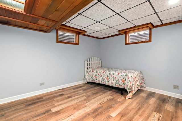 bedroom with a drop ceiling, baseboards, and wood finished floors