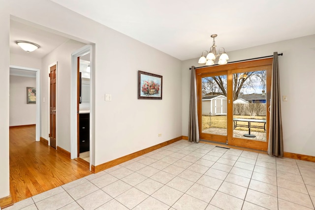 unfurnished dining area featuring visible vents, a notable chandelier, baseboards, and light tile patterned floors