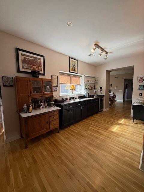 bar with light wood finished floors and a sink