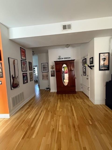 hall featuring light wood-type flooring, visible vents, and baseboards