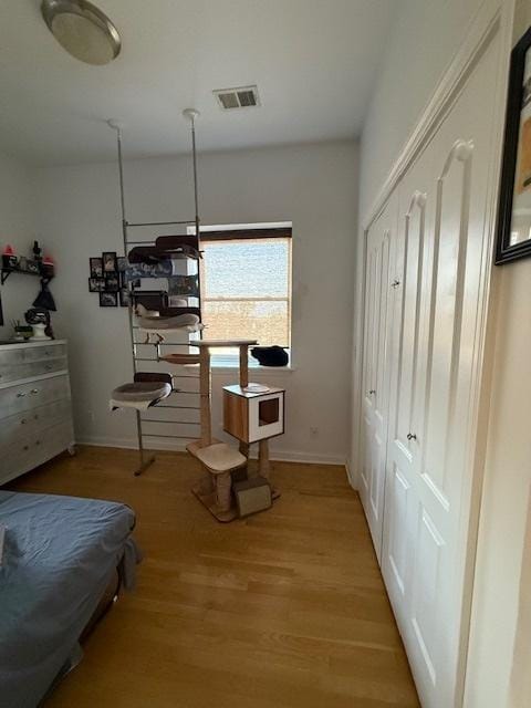 bedroom with light wood-style flooring, visible vents, and baseboards