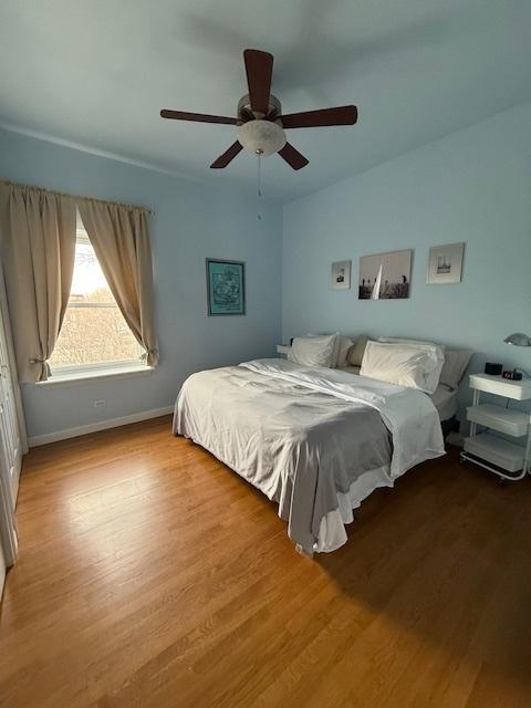 bedroom with wood finished floors, a ceiling fan, and baseboards