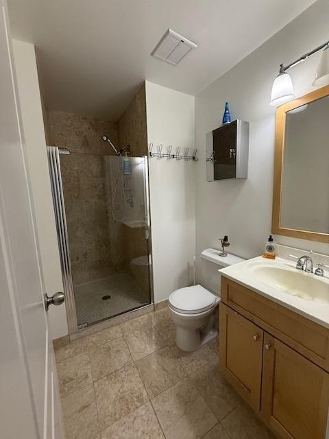 full bathroom with visible vents, toilet, a shower stall, and vanity