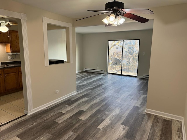 spare room with a baseboard radiator, a ceiling fan, and wood finished floors