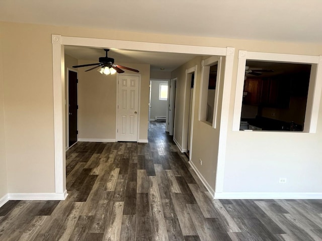 corridor featuring a baseboard radiator, baseboards, and dark wood-type flooring