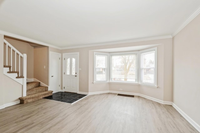 foyer featuring stairs, ornamental molding, wood finished floors, and visible vents