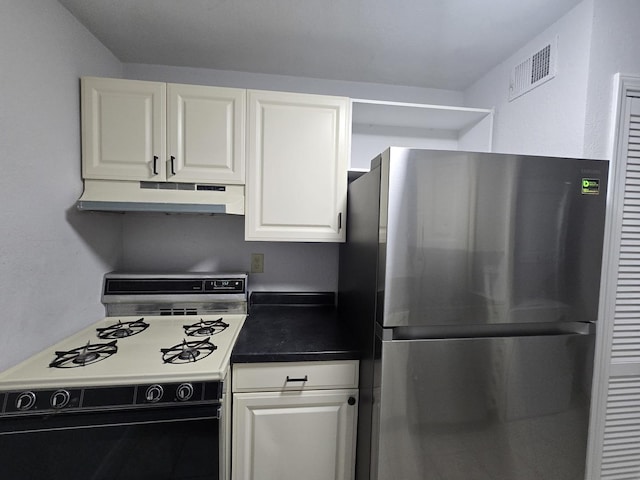 kitchen featuring visible vents, freestanding refrigerator, white cabinetry, gas range, and under cabinet range hood