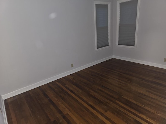 empty room featuring dark wood finished floors and baseboards