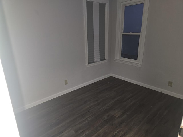 spare room featuring dark wood finished floors and baseboards