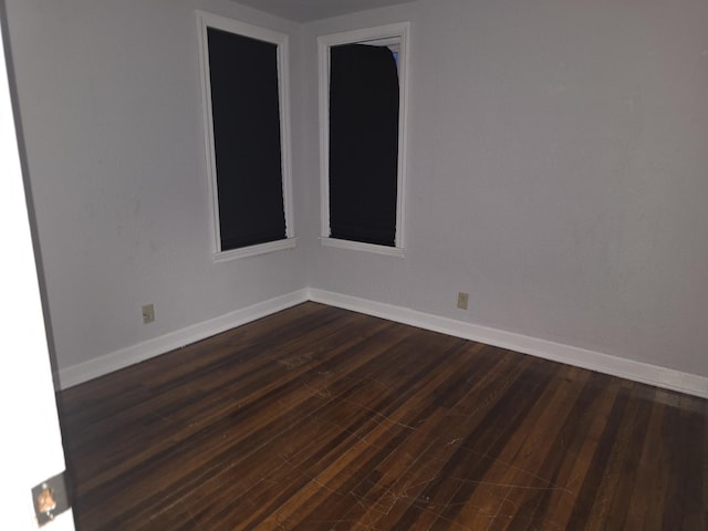 unfurnished room with dark wood-style flooring and baseboards