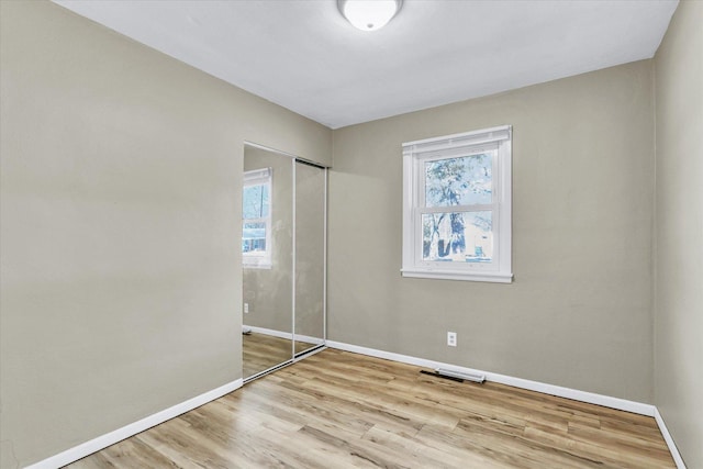 unfurnished bedroom with light wood-type flooring, visible vents, baseboards, and a closet