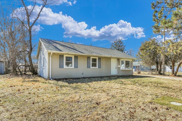 ranch-style home featuring a front lawn and roof with shingles