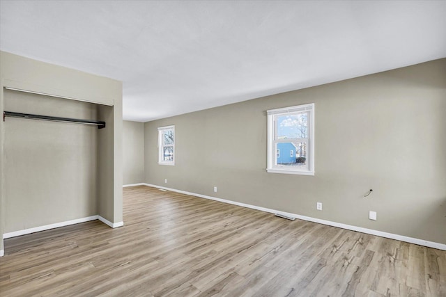 unfurnished bedroom with light wood-style floors, baseboards, and a closet