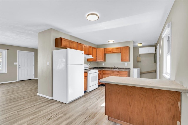 kitchen featuring white appliances, light countertops, plenty of natural light, and light wood finished floors