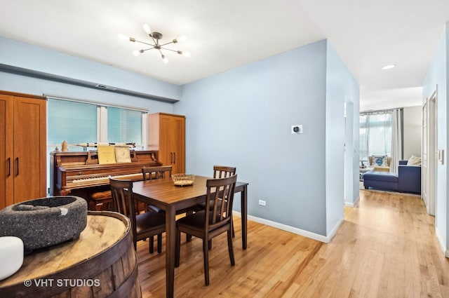 dining room featuring light wood-type flooring, a notable chandelier, and baseboards