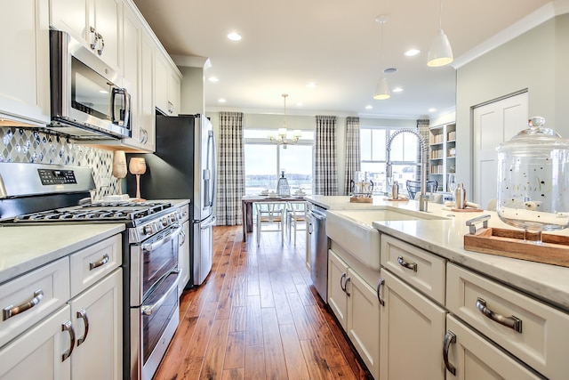 kitchen featuring white cabinets, hanging light fixtures, a view of city, stainless steel appliances, and crown molding