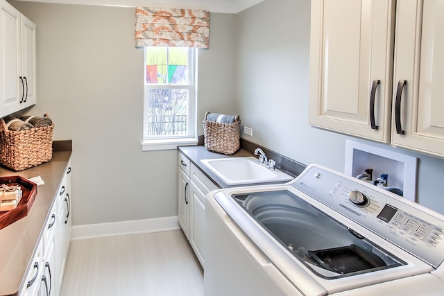 clothes washing area featuring cabinet space, baseboards, a sink, and washing machine and clothes dryer